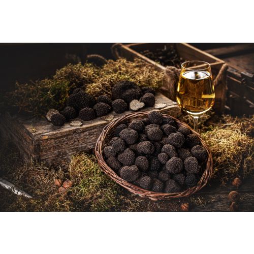 Zwarte truffels in een mand met een glas wijn ernaast.